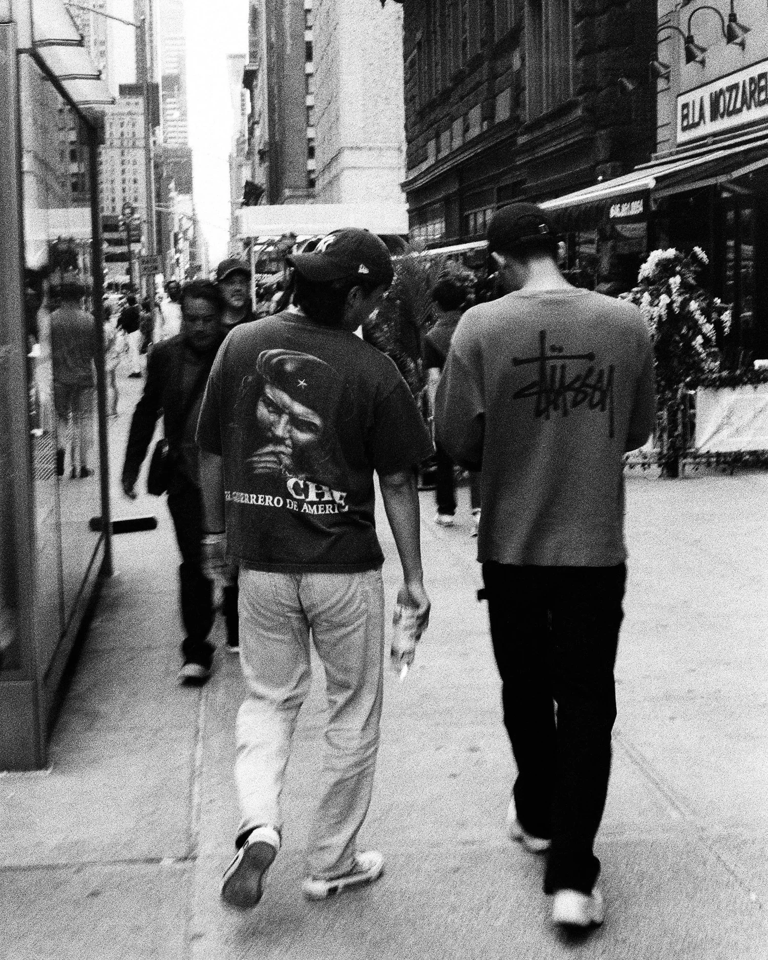 Black and white photograph of two friends walking through midtown Manhattan